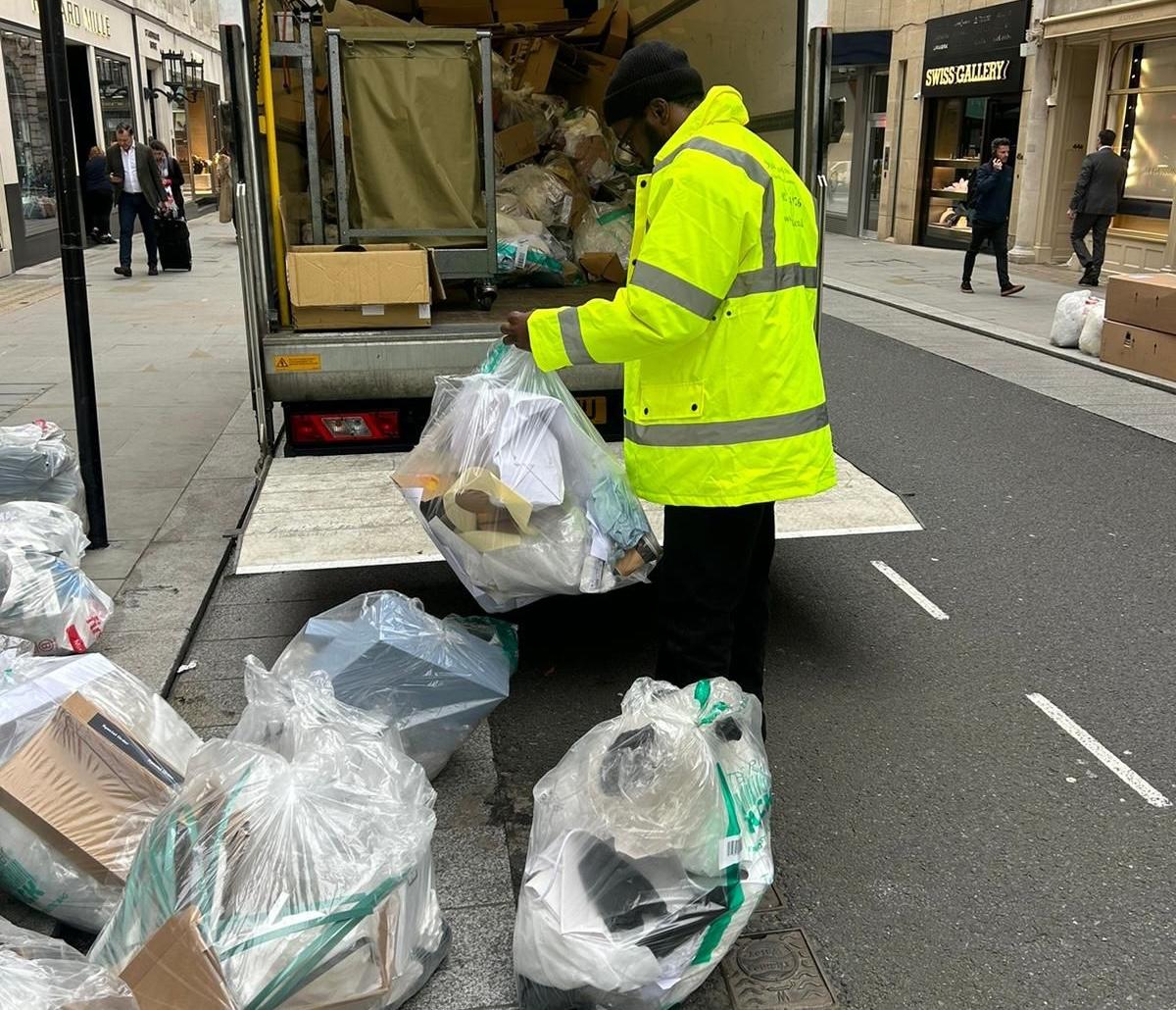 DWT operative loading tracked waste bags into a collection vehicle on a London street